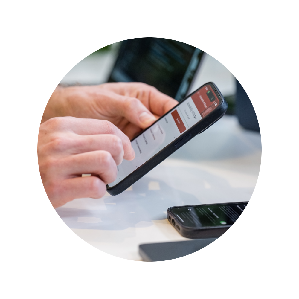 Person using a smartphone during an app accessibility check, with a second phone on the table.