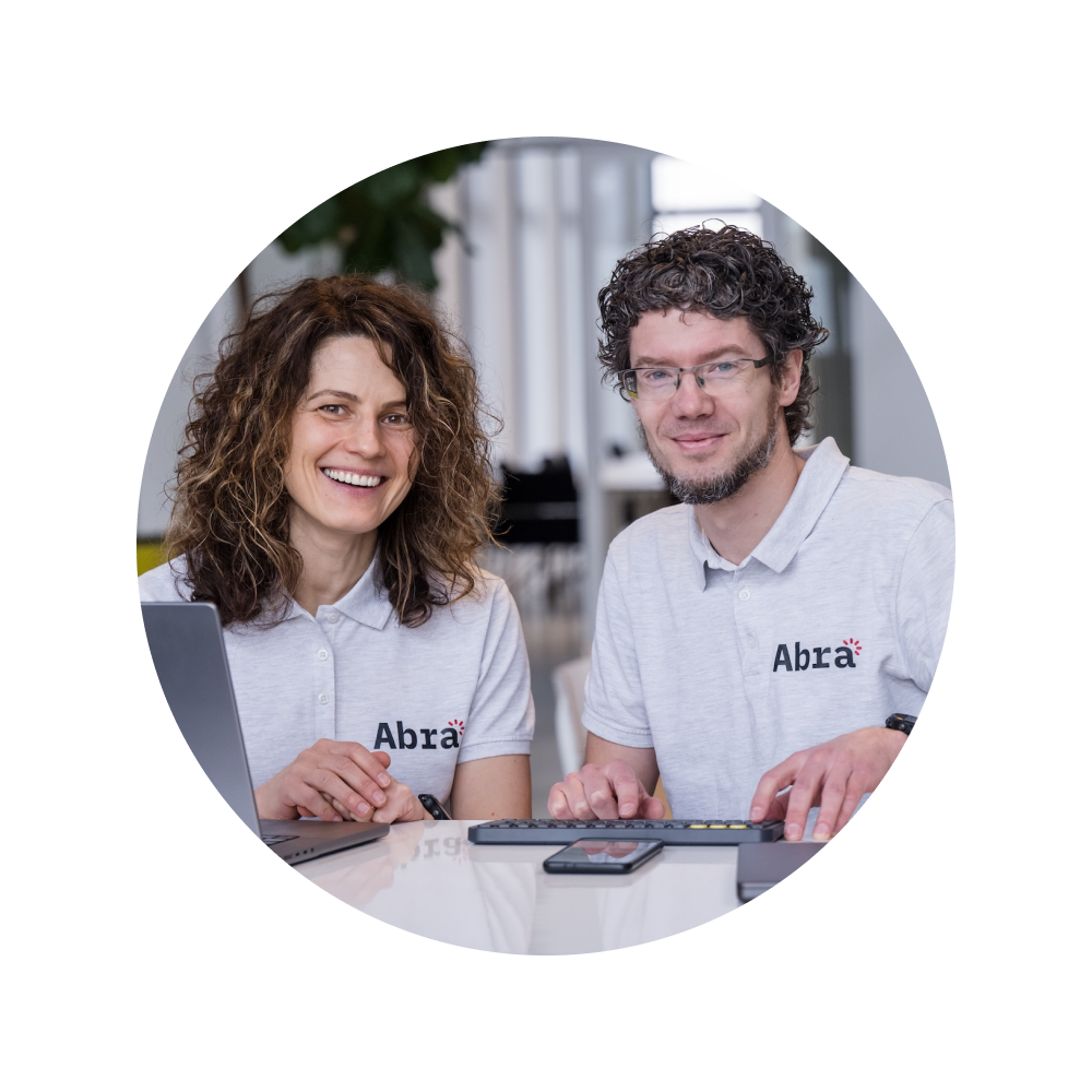 Tanya van Workum and Paul van Workum sitting behind the desk and wearing Abra t-shirts